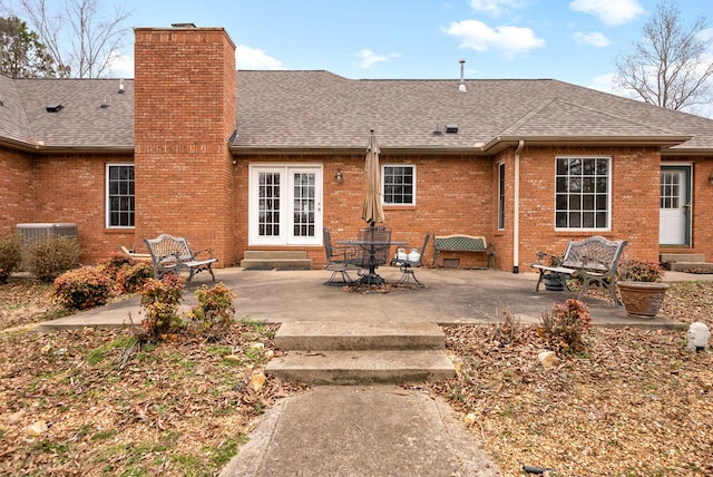 rear view of property with roof with shingles, central AC, a chimney, entry steps, and brick siding