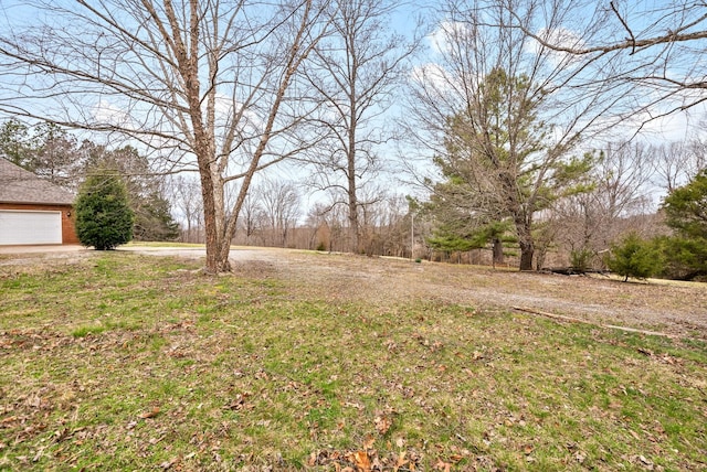 view of yard with a garage and dirt driveway