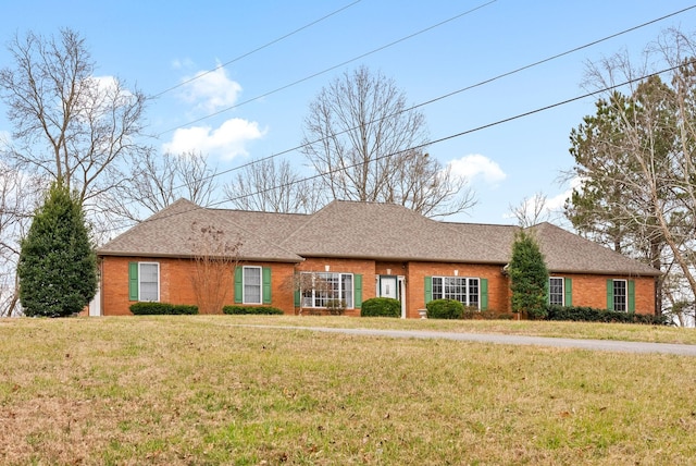 single story home featuring brick siding, a front yard, and roof with shingles