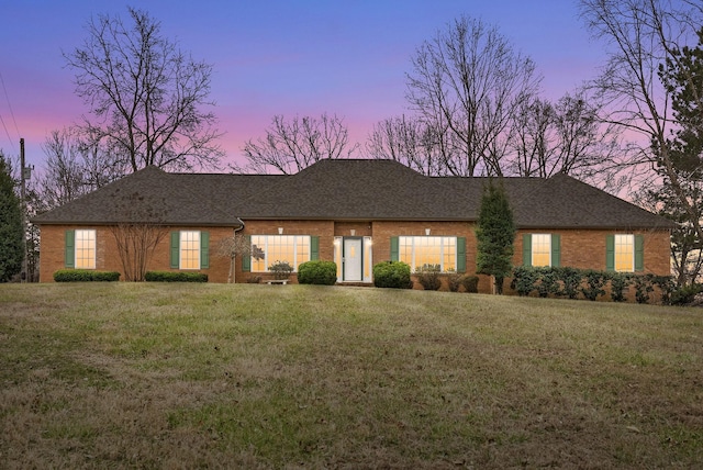 ranch-style house with brick siding, a shingled roof, and a yard