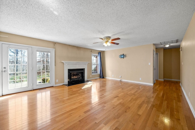 unfurnished living room with visible vents, plenty of natural light, a fireplace, and light wood-type flooring