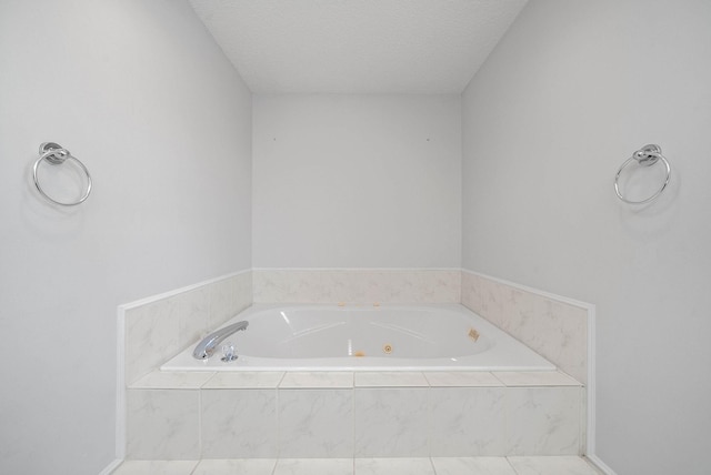 bathroom with a tub with jets and a textured ceiling