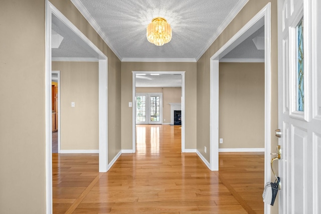 entrance foyer featuring light wood-type flooring, a fireplace with flush hearth, a textured ceiling, and baseboards