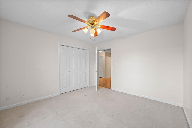 unfurnished bedroom with a textured ceiling, a closet, carpet, baseboards, and ceiling fan