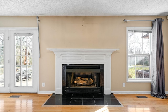 details featuring a fireplace with flush hearth, a textured ceiling, visible vents, and wood finished floors