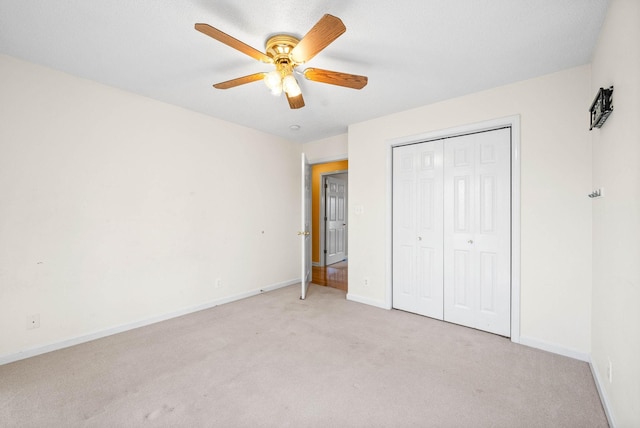 unfurnished bedroom with light carpet, a closet, baseboards, and a ceiling fan