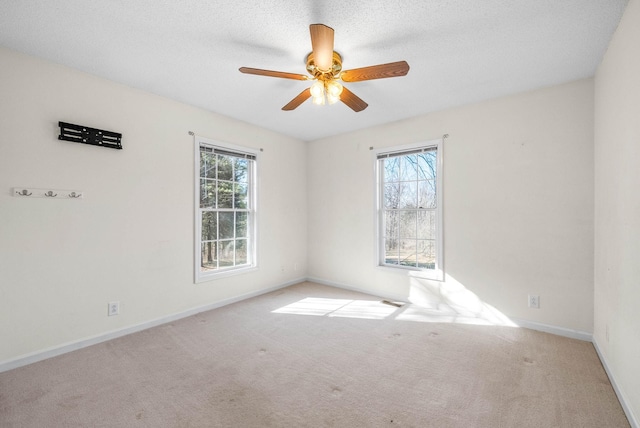 empty room with a textured ceiling, carpet, baseboards, and ceiling fan