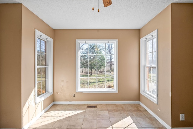 interior space with light tile patterned floors, baseboards, visible vents, ceiling fan, and a textured ceiling