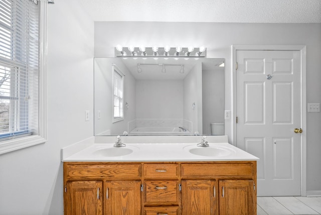 bathroom with a textured ceiling, a bath, and a sink