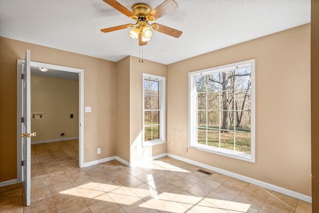 empty room featuring light tile patterned floors, a ceiling fan, baseboards, visible vents, and a textured ceiling