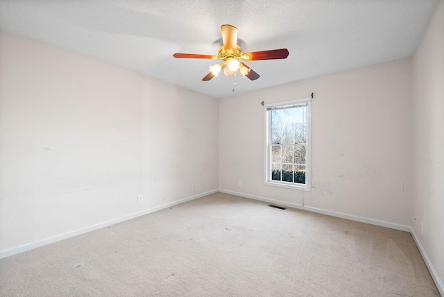 empty room with baseboards, visible vents, carpet floors, ceiling fan, and a textured ceiling