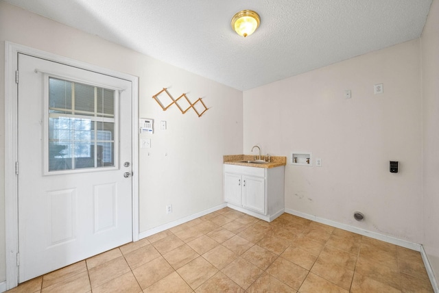 laundry room with a sink, a textured ceiling, cabinet space, light tile patterned floors, and hookup for a washing machine