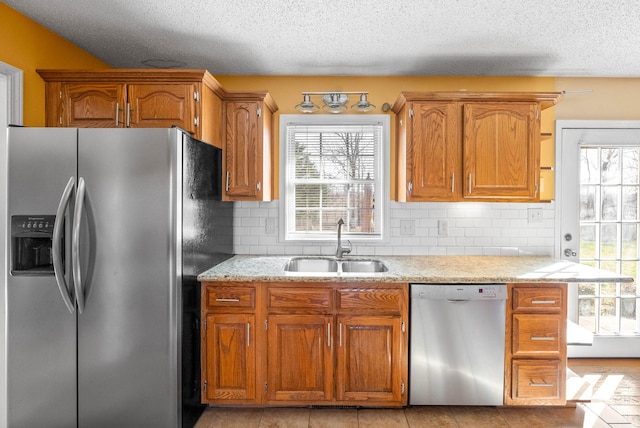 kitchen featuring a sink, a healthy amount of sunlight, brown cabinets, and stainless steel appliances