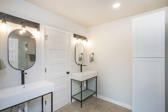 full bathroom featuring a shower, recessed lighting, two sinks, and baseboards