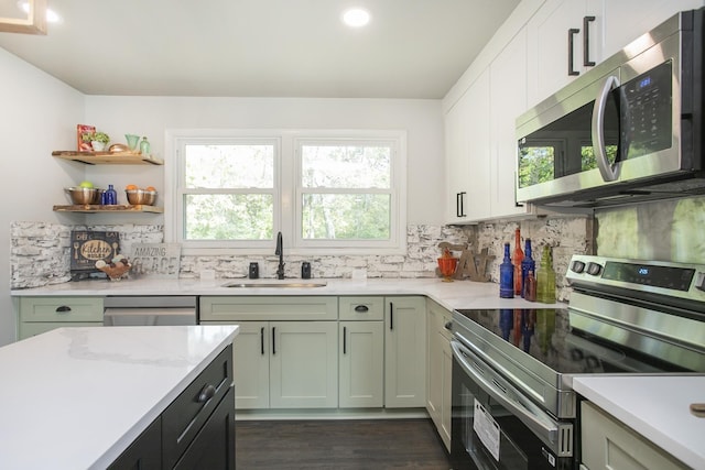 kitchen with stainless steel appliances, light countertops, a sink, and decorative backsplash