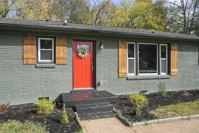 view of exterior entry with crawl space and brick siding