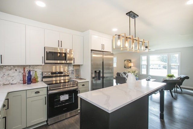 kitchen featuring stainless steel appliances, dark wood-type flooring, a kitchen island, backsplash, and light stone countertops