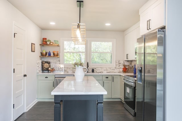 kitchen featuring stainless steel appliances, dark wood-type flooring, a sink, decorative backsplash, and a center island