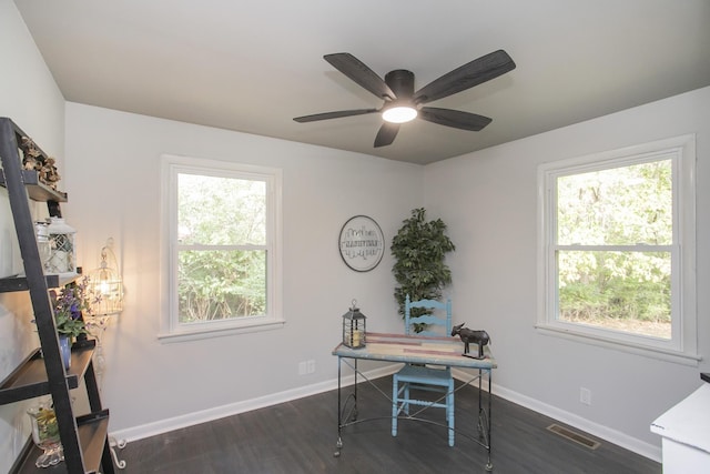 home office with dark wood-type flooring, a ceiling fan, visible vents, and baseboards