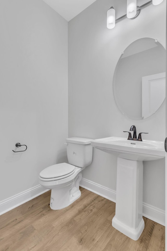 half bathroom featuring toilet, baseboards, and wood finished floors