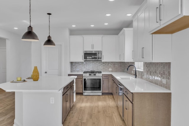 kitchen with light countertops, light wood-style flooring, appliances with stainless steel finishes, white cabinets, and a sink