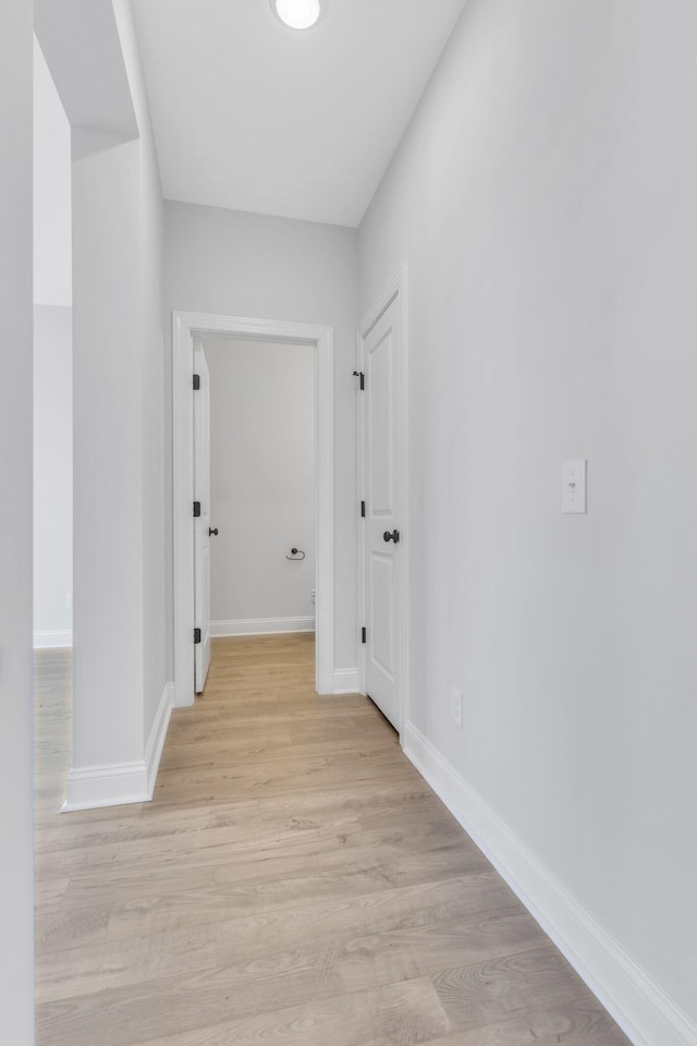 hallway featuring light wood-style flooring and baseboards