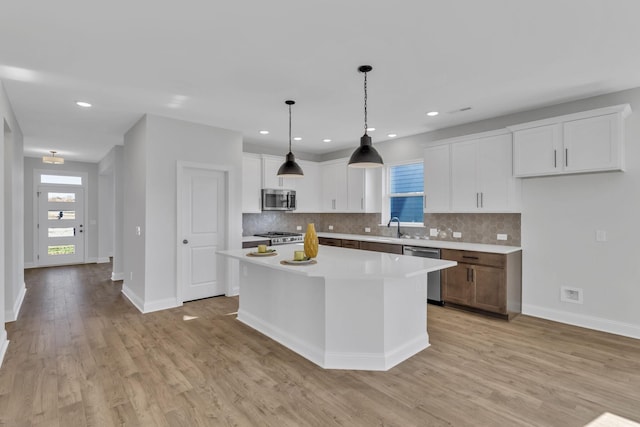 kitchen featuring light wood-style floors, appliances with stainless steel finishes, white cabinets, and light countertops