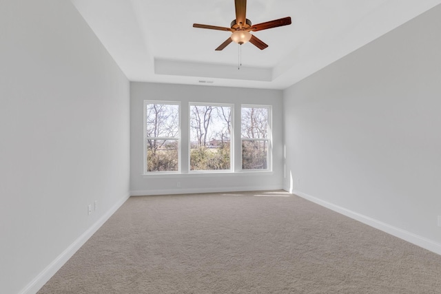 empty room featuring visible vents, baseboards, a raised ceiling, ceiling fan, and carpet floors