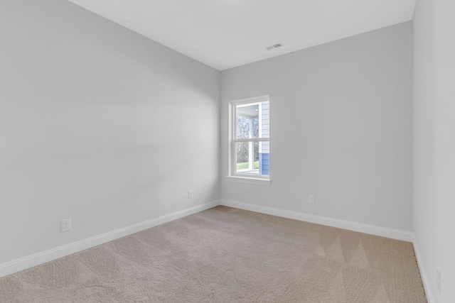 spare room with carpet flooring, visible vents, and baseboards