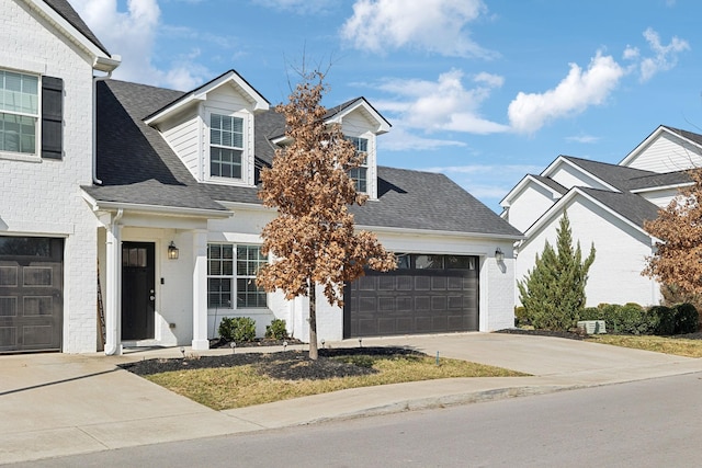 view of front of property with a garage, concrete driveway, brick siding, and roof with shingles