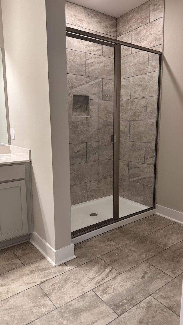 bathroom featuring a shower stall, baseboards, and vanity