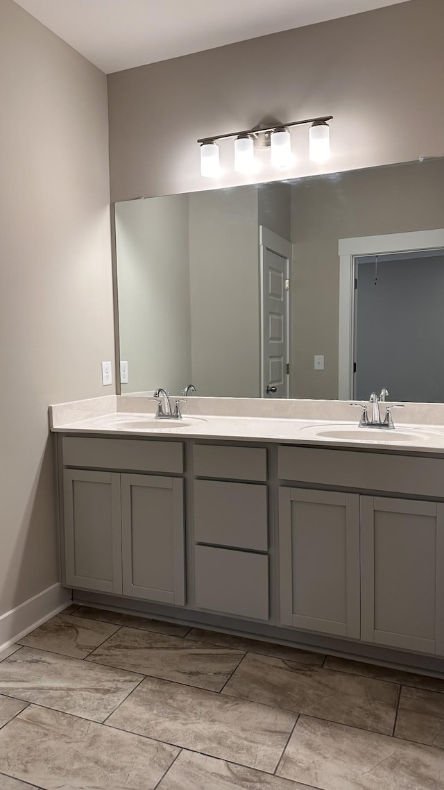 full bath with a sink, baseboards, and double vanity