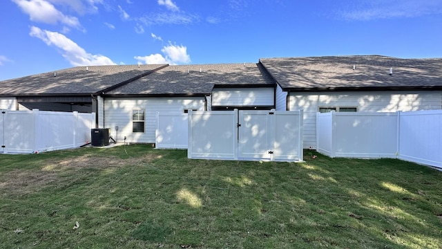 rear view of house featuring a fenced backyard, a gate, central AC unit, and a yard