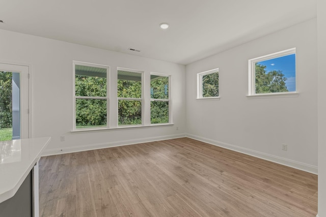 unfurnished room featuring light wood-style floors, visible vents, and baseboards