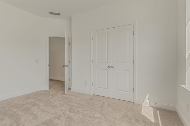 unfurnished bedroom featuring light carpet, baseboards, visible vents, and a closet