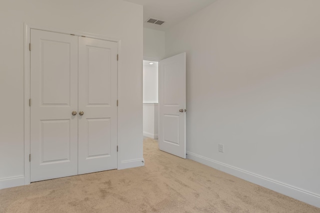 unfurnished bedroom with light carpet, baseboards, visible vents, and a closet