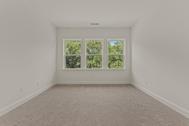 unfurnished room with carpet, visible vents, and baseboards