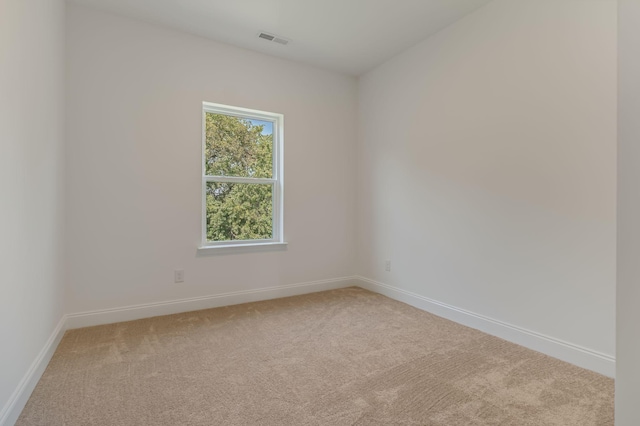 spare room with carpet floors, visible vents, and baseboards