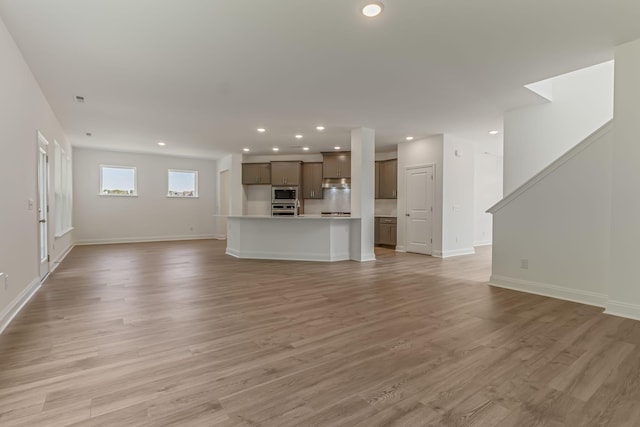 unfurnished living room featuring baseboards, light wood-type flooring, and recessed lighting