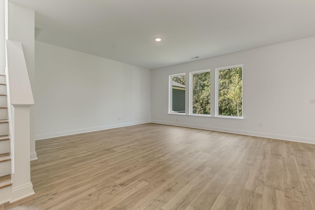 unfurnished room featuring light wood-type flooring, recessed lighting, baseboards, and stairs