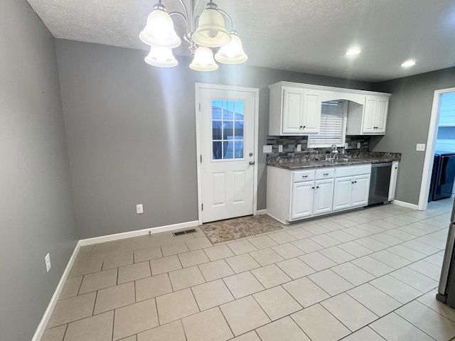 kitchen featuring baseboards, visible vents, white cabinets, dishwasher, and a sink