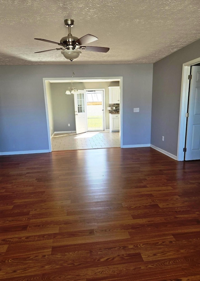 empty room featuring ceiling fan, a textured ceiling, baseboards, and wood finished floors