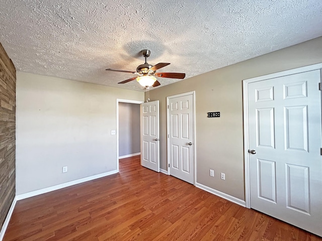 unfurnished bedroom featuring a ceiling fan, wood finished floors, baseboards, and a textured ceiling
