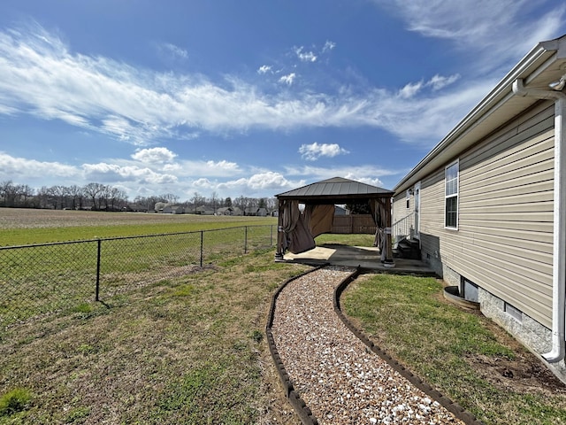 view of yard featuring a rural view, a gazebo, a fenced backyard, and a patio