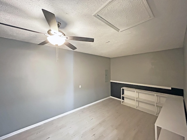 empty room with a ceiling fan, wood finished floors, baseboards, and a textured ceiling