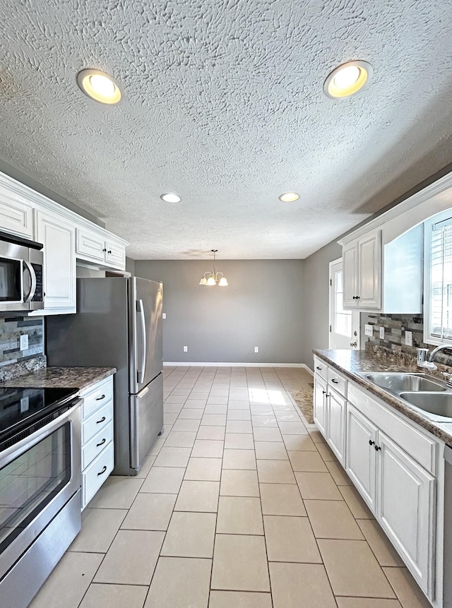 kitchen featuring backsplash, appliances with stainless steel finishes, white cabinets, and a sink