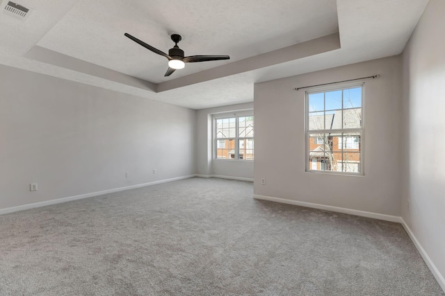 carpeted empty room with a tray ceiling, visible vents, ceiling fan, a textured ceiling, and baseboards