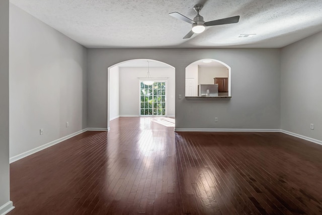 empty room with ceiling fan, baseboards, arched walkways, and dark wood-type flooring