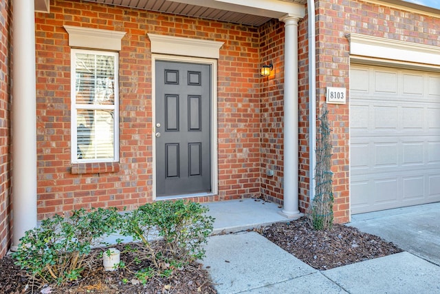 doorway to property with a garage and brick siding