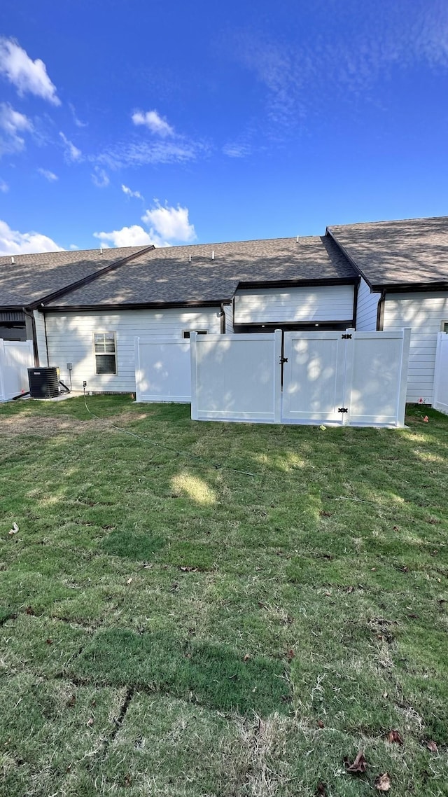 view of side of property featuring a shingled roof and a yard